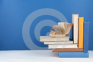 Open book, hardback colorful books on wooden table, blue background. Back to school. Copy space for text. Education business