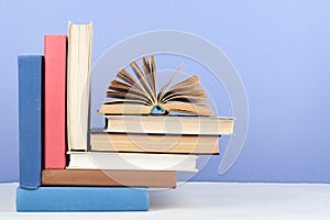 Open book, hardback colorful books on wooden table, blue background. Back to school. Copy space for text. Education business