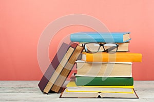 Open book, hardback colorful books on wooden table. Glasses. Back to school. Copy space for text. Education business concept