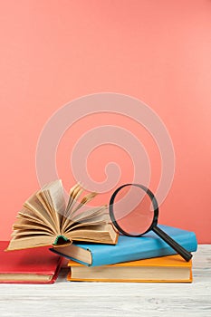 Open book, hardback colorful books on wooden table. Magnifier. Back to school. Copy space for text. Education business