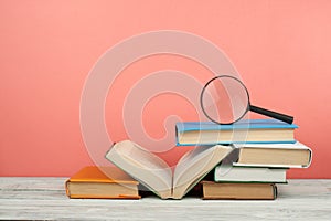 Open book, hardback colorful books on wooden table. Magnifier. Back to school. Copy space for text. Education business concept