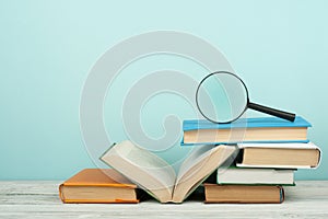 Open book, hardback colorful books on wooden table. Magnifier. Back to school. Copy space for text. Education business concept