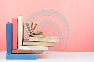 Open book, hardback colorful books on wooden table, red, pink background. Back to school. Copy space for text. Education