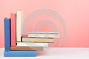 Open book, hardback colorful books on wooden table, red, pink background. Back to school. Copy space for text. Education