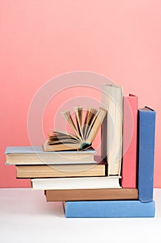 Open book, hardback colorful books on wooden table, red, pink background. Back to school. Copy space for text. Education