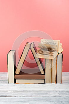 Open book, hardback colorful books on wooden table, red, pink background. Back to school. Copy space for text. Education