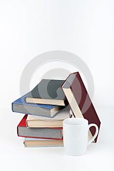 Open book, hardback colorful books on wooden table, white background. Back to school. Cup. Copy space for text