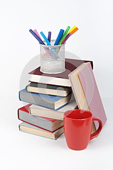 Open book, hardback colorful books on wooden table, white background. Back to school. Pens, pencils, cup. Copy space for