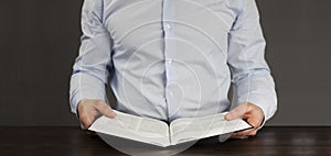 The open book is the holy bible. Young man in a shirt. Prayer and Scripture Reading