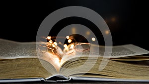 Open book and light on it on black background, Old book. Opened magic book with magic light on a black background
