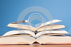 open book with magnifying glass on wooden desk in information library of school or university, concept for education,reading ,