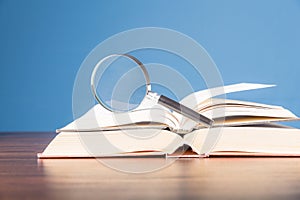 open book with magnifying glass on wooden desk in information library of school or university, concept for education,reading ,