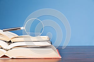 open book with magnifying glass on wooden desk in information library of school or university, concept for education,reading ,