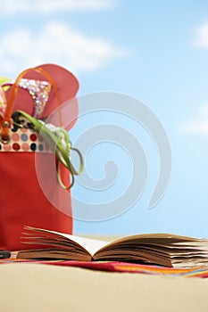 Open book next to beach bag on beach close up