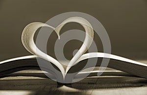 Open book with pages forming heart shape .