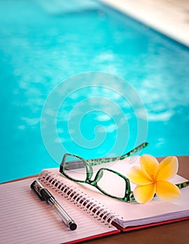 Open Book, Pen and Glasses on The Table Beside Swimming Pool