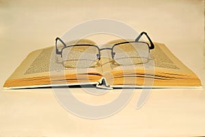 Open book and reading glasses on white background