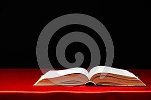 Open book on red and black background. The wisdom of generations, knowledge and love of reading, a place for text.