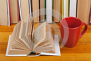 Open book, red cup hardback colorful books on wooden table. Back to school. Copy space for text. Education business