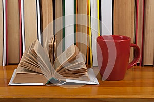 Open book, red cup hardback colorful books on wooden table. Back to school. Copy space for text. Education business