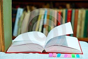 Open book, stack of hardback books on table. Top view.