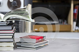 Open book, stack of hardback books on table. Top view.