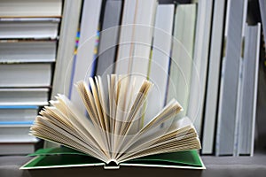 Open book, stack of hardback books on table. Top view.