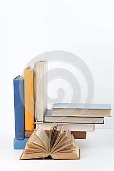 Open book, stack, hardback colorful books on wooden table, white background. Back to school. Copy space for text