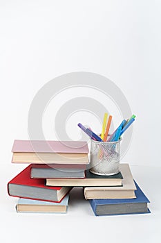 Open book, stack, hardback colorful books on wooden table, white background. Back to school. Pens, pencils, Copy space for text.
