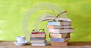 Open Book and a stack of multicolored hardback books with a cup of coffee, reading education, literature copy space