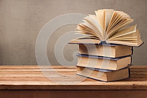 Open book and stack of old books on wooden table