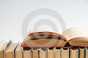 Open book on white background, hardback books on wooden table. E