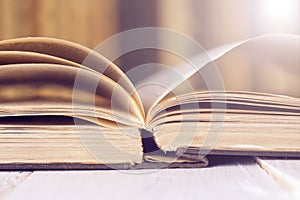 Open book on wood planks over abstract light background.