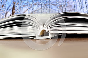 Open book on a wood table over blue winter light background