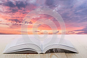 Open book at wooden table on natural blurred background