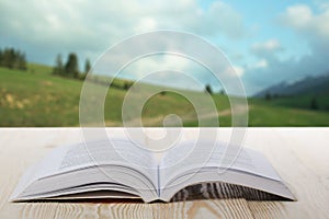 Open book on wooden table on natural blurred background. Back to school. Copy Space