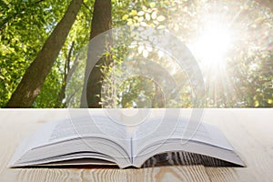 Open book on wooden table on natural blurred background. Back to school. Copy Space