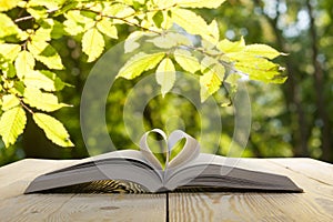 Open book on wooden table on natural blurred background. Heart book page. Back to school. Copy Space