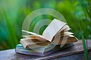 Open Book on a Wooden Table Outdoor on a blurred natural background