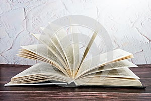 Open book on a wooden table. Toned. Side view.