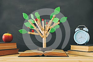 open book and wooden tree puzzle over blackboard background. education and knowledge concept.