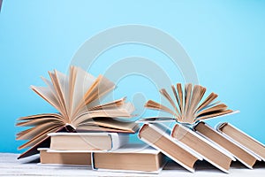 Open books, hardback colorful books on wooden table. blue background. Back to school. Copy space for text. Education business