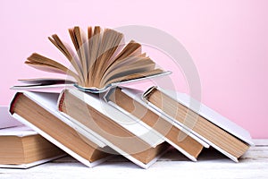 Open books, hardback colorful books on wooden table. pink background. Back to school. Copy space for text. Education business