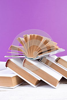 Open books, hardback colorful books on wooden table. purple background. Back to school. Copy space for text. Education business