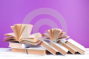 Open books, hardback colorful books on wooden table. purple background. Back to school. Education business