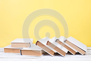 Open books, hardback colorful books on wooden table. yellow background. Back to school. Copy space for text. Education business