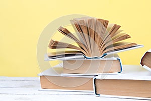 Open books, hardback colorful books on wooden table. yellow background. Back to school. Education business