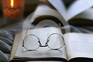 Open Books, Reading Glasses and Lit Candle