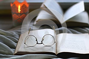 Open Books, Reading Glasses and Lit Candle