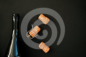 An open bottle of champagne or wine on a black background. The cork from the bottle is lying next to it
